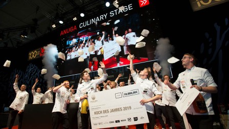 Group picture Chef of the year 2019 All cooks are assembled on stage and throw their toques into the air. The winners are holding a big check.